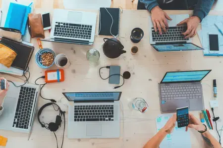 Sur une table de réunion, des collaborateurs travaillent sur un projet digital